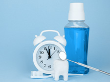 toothbrush, clock, and mouthwash sitting on a table