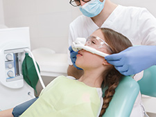 Young patient in dentists chair wearing a sedation mask